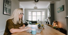 A woman using a laptop at a table in her home.