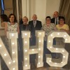 NHS staff standing together behind giant letters that spell NHS.
