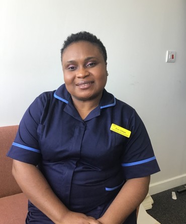 Eve in her work uniform, sitting on a chair in an office.