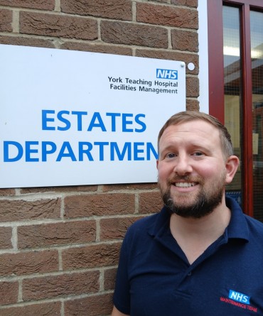 Tom standing by the 'Estates Department' building sign at Scarborough Hospital.