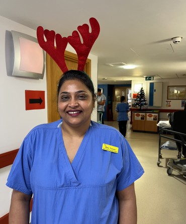 Mary wearing reindeer antlers and her work scrubs while standing in a hospital corridor.