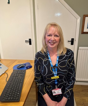 Cathy sitting next to a desk with her computer beside her