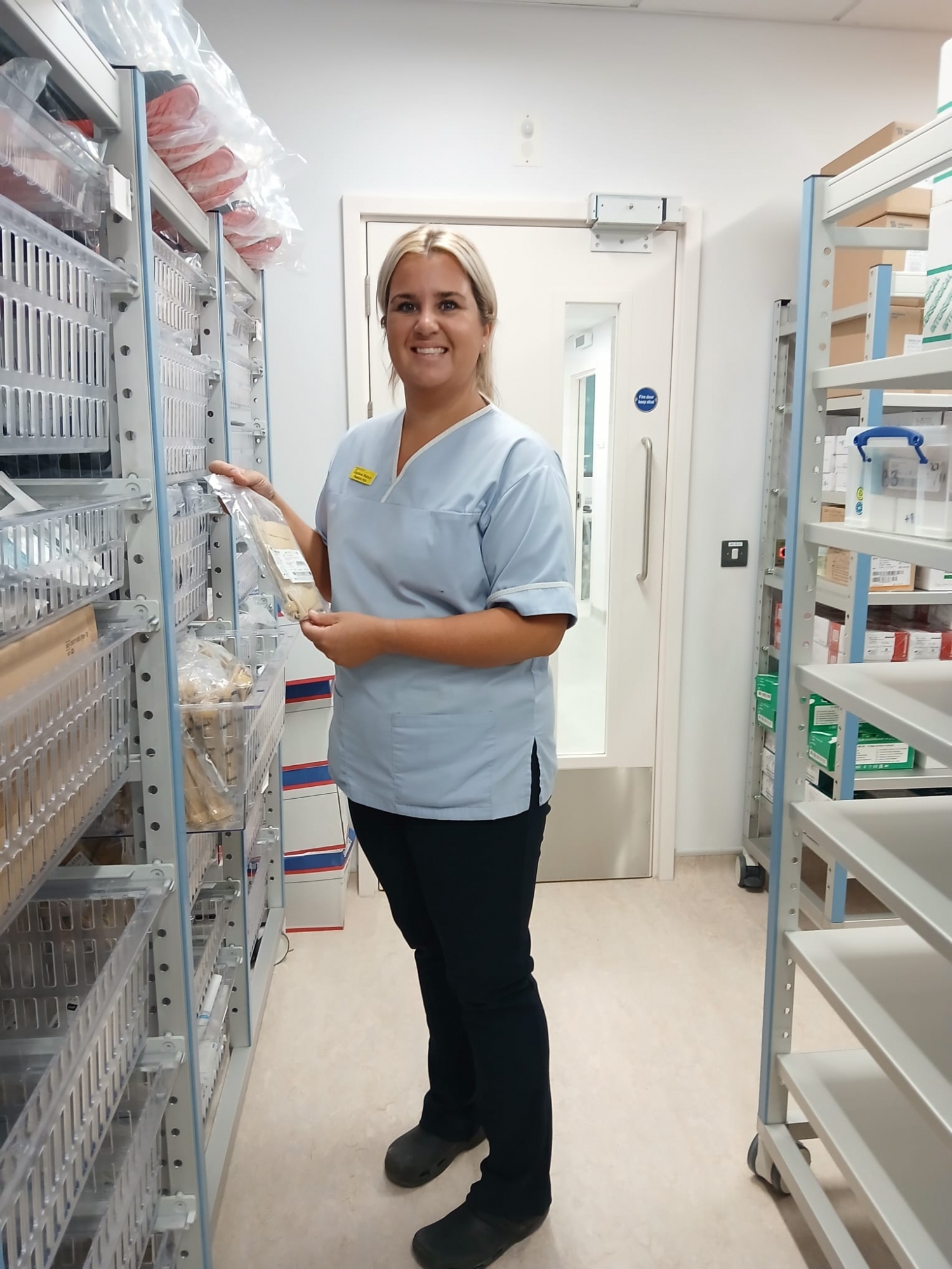 Jaydene Louth, Paediatric Healthcare Assistant standing in a supplies room.